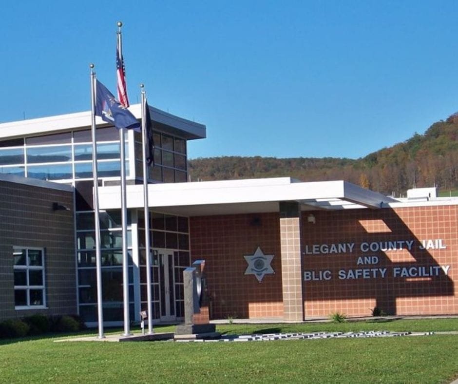 Exterior view of the Allegany County Jail and Public Safety Facility building with flags and entrance lawn.