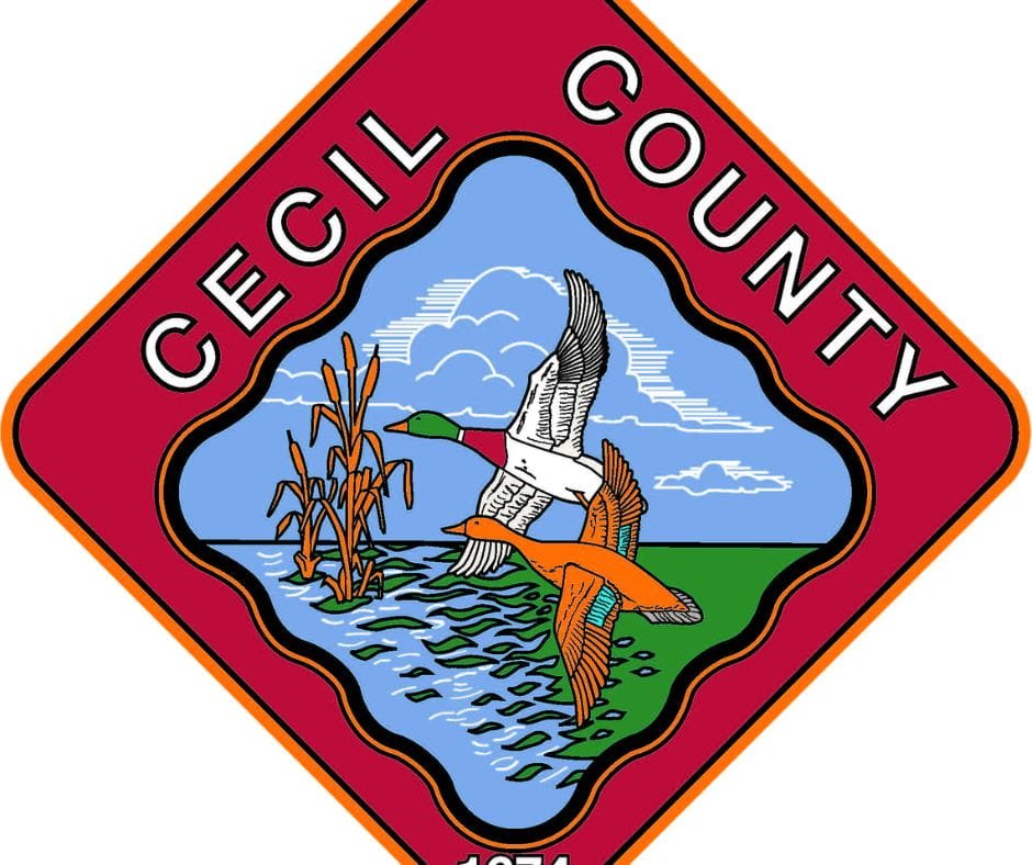 The official diamond-shaped seal of Cecil County featuring two ducks flying over water with cattails, bordered in red with white text