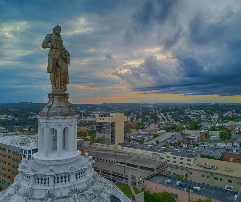 Statue atop a historic courthouse dome overlooking downtown Cumberland, Maryland at sunset.